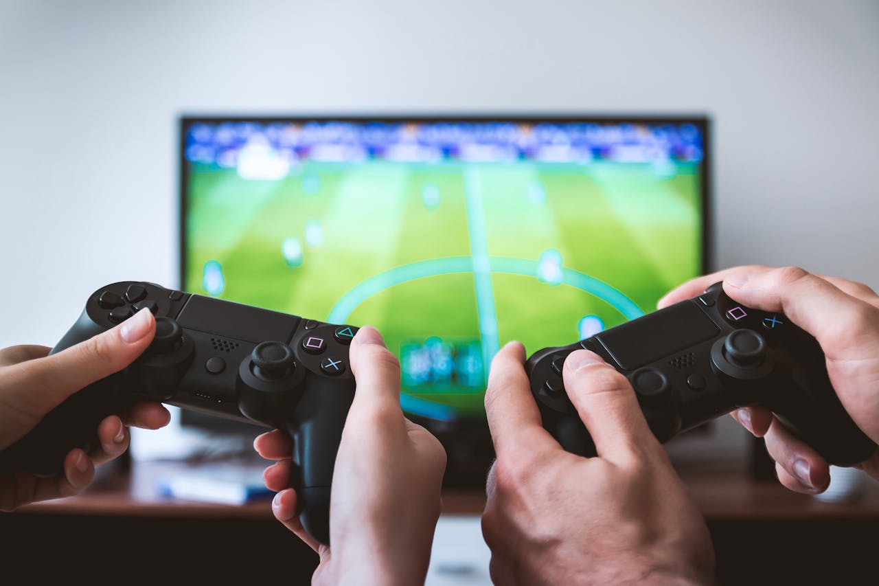 Two People holding Black Gaming Consoles